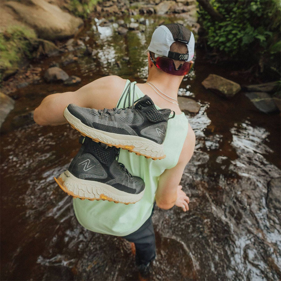 Man walking in water holding shoes